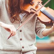 woman-in-gray-cardigan-playing-a-violin-during-daytime-111287
